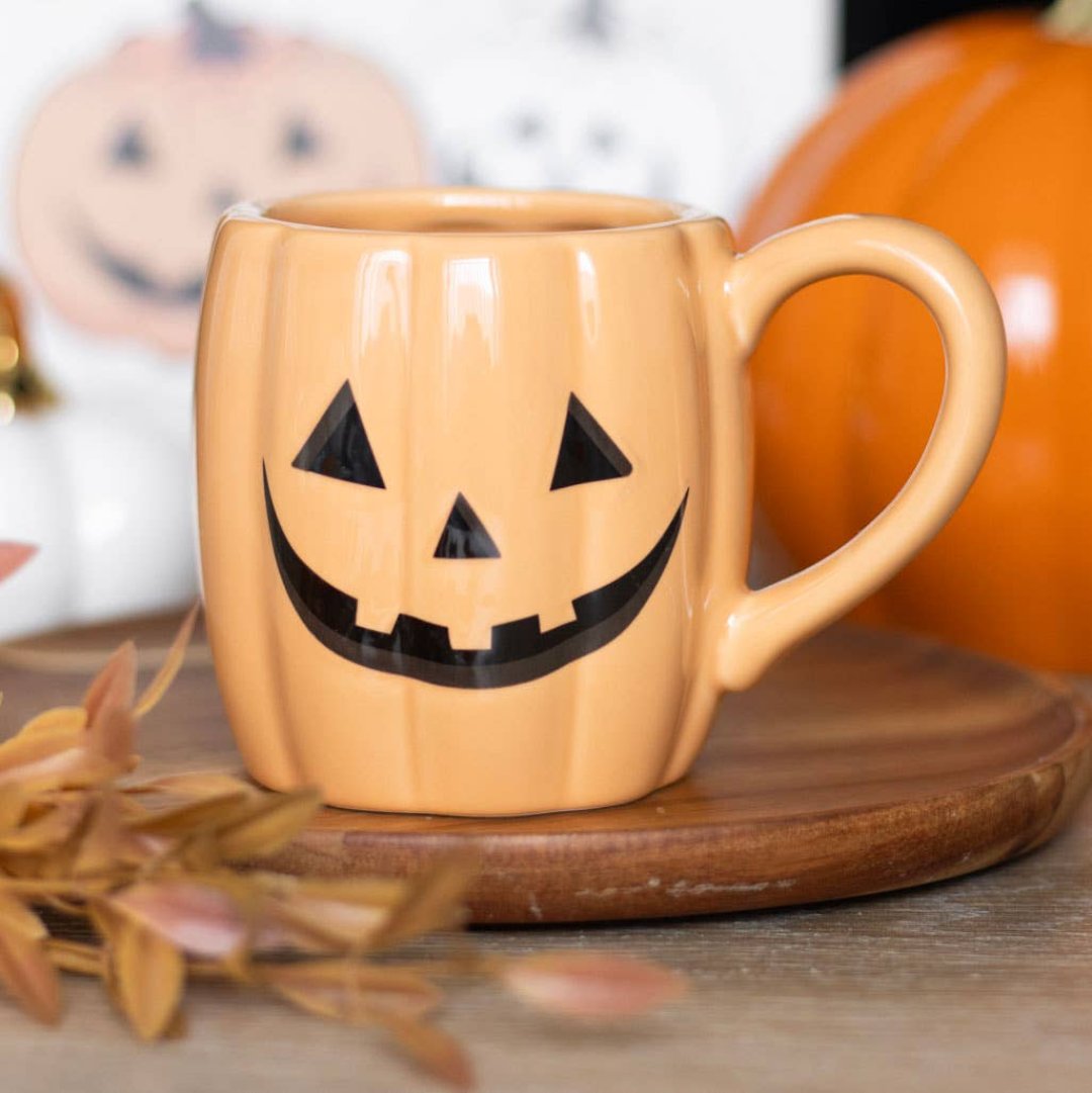 orange mug that looks like a pumpkin with a happy carved face