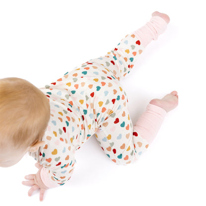 Side view of baby crawling in Rainbow Hearts bamboo footie romper.