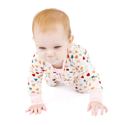 Baby crawling in Rainbow Hearts bamboo convertible footie romper.