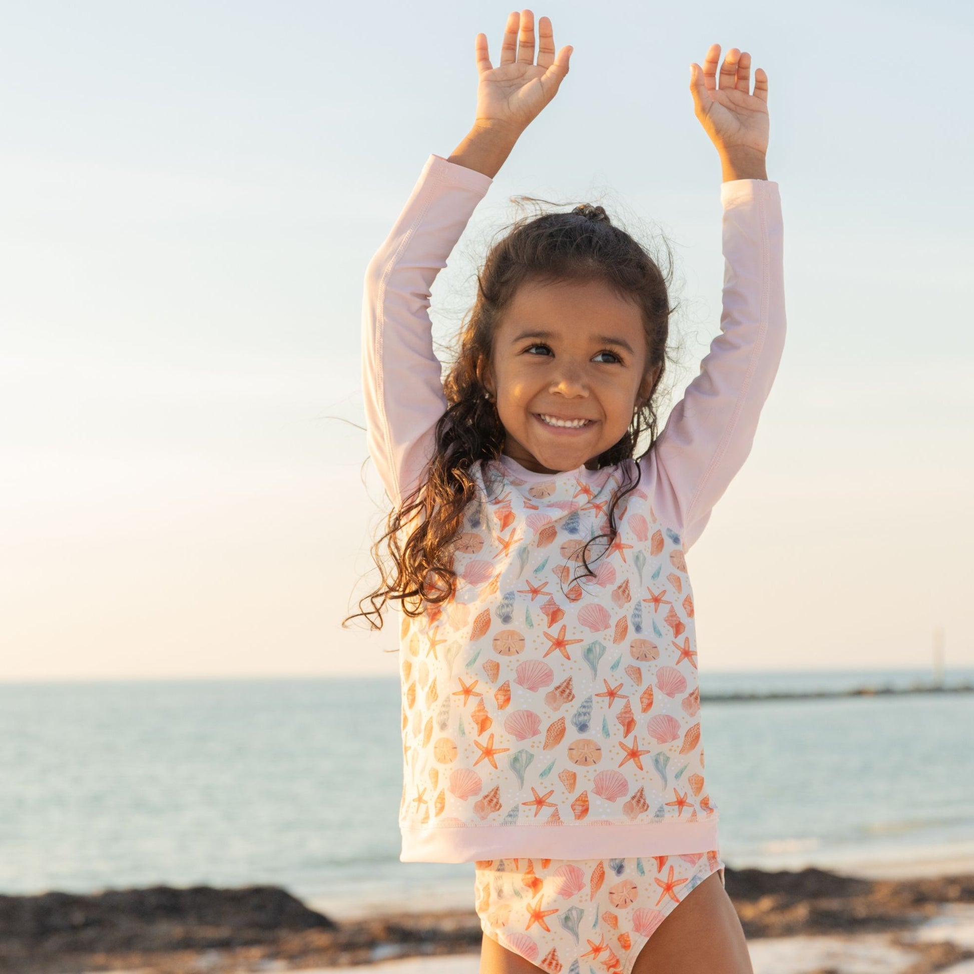 Girls wearing sandy seashells rash guard at the beach 