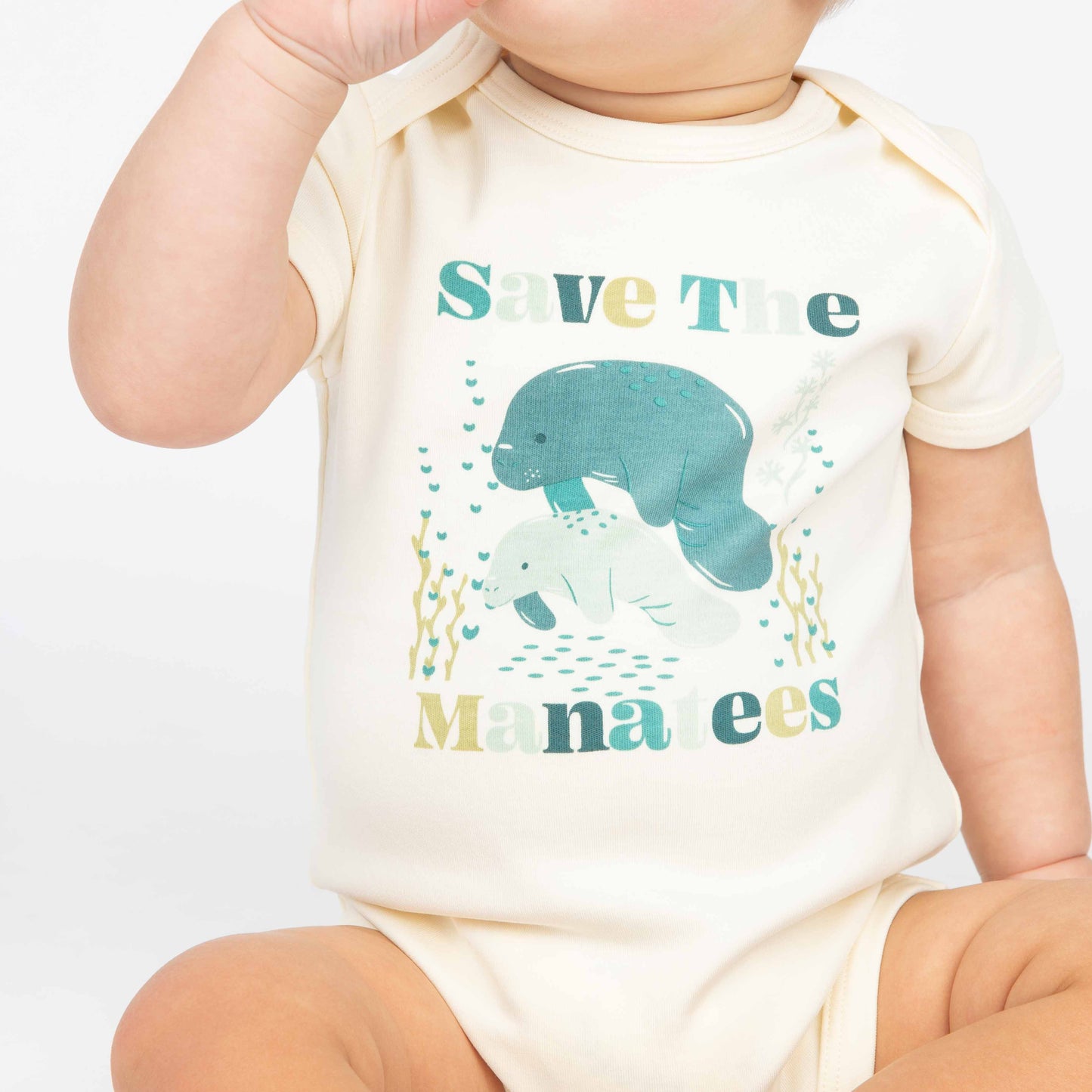 Baby wearing a Save the Manatees cotton onesie with a cute manatee print, featuring soft, eco-friendly fabric on a white background.