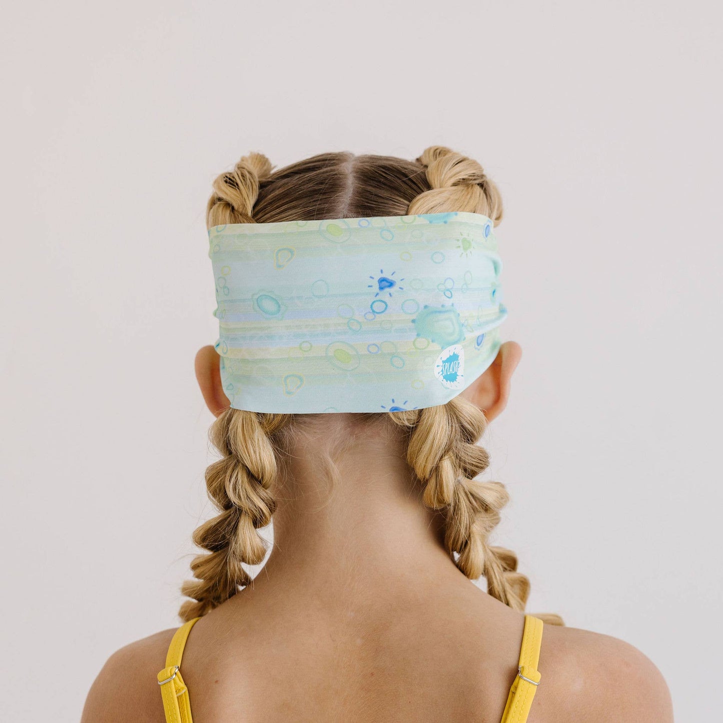 Person wearing a colorful headband with braided hair on a plain background