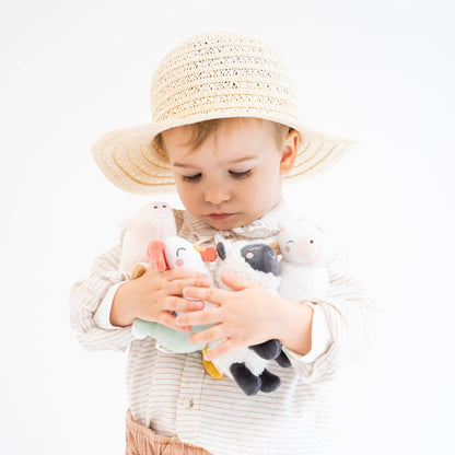 Child wearing a straw hat and holding plush toys on a white background