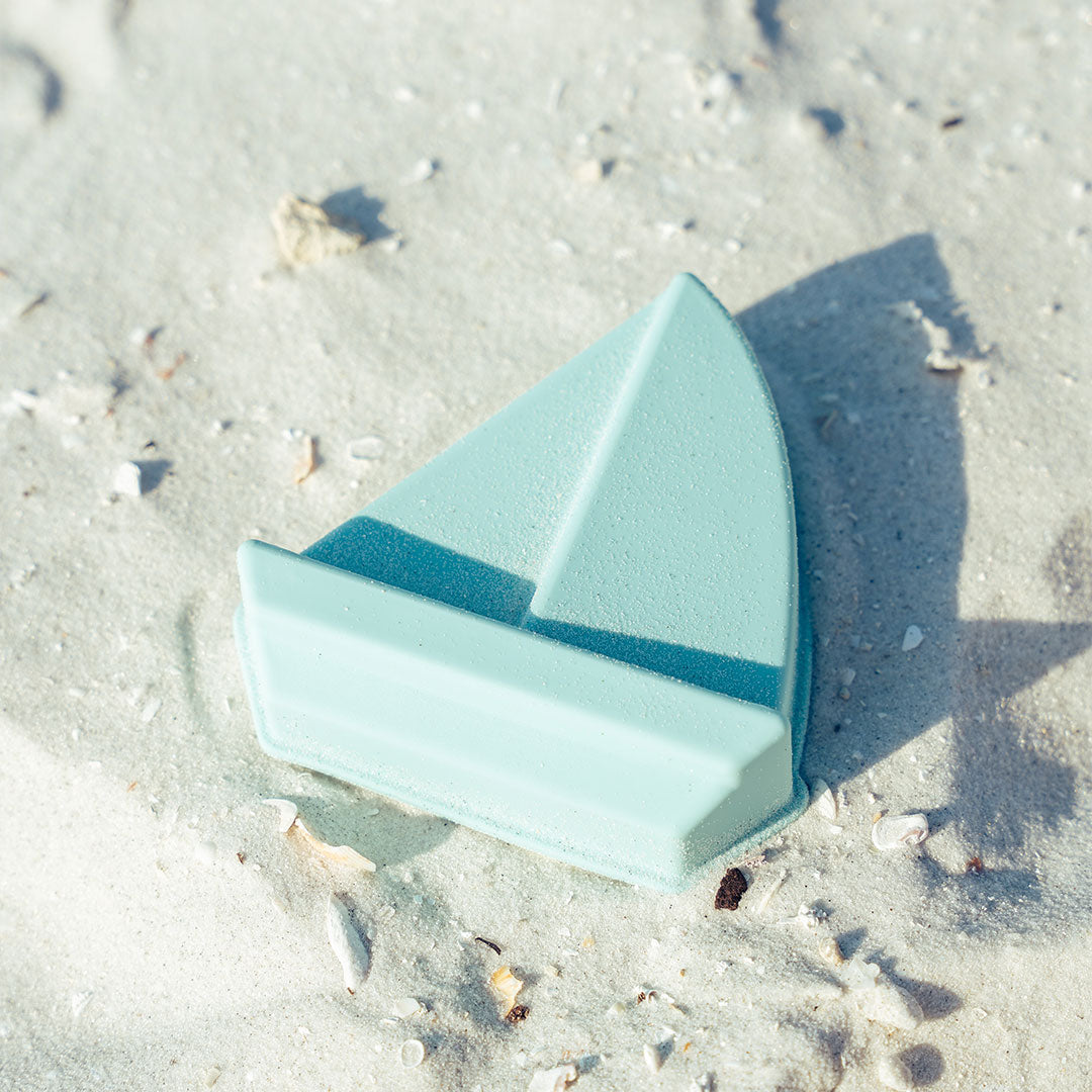 the blue sailboat lays in the sand.