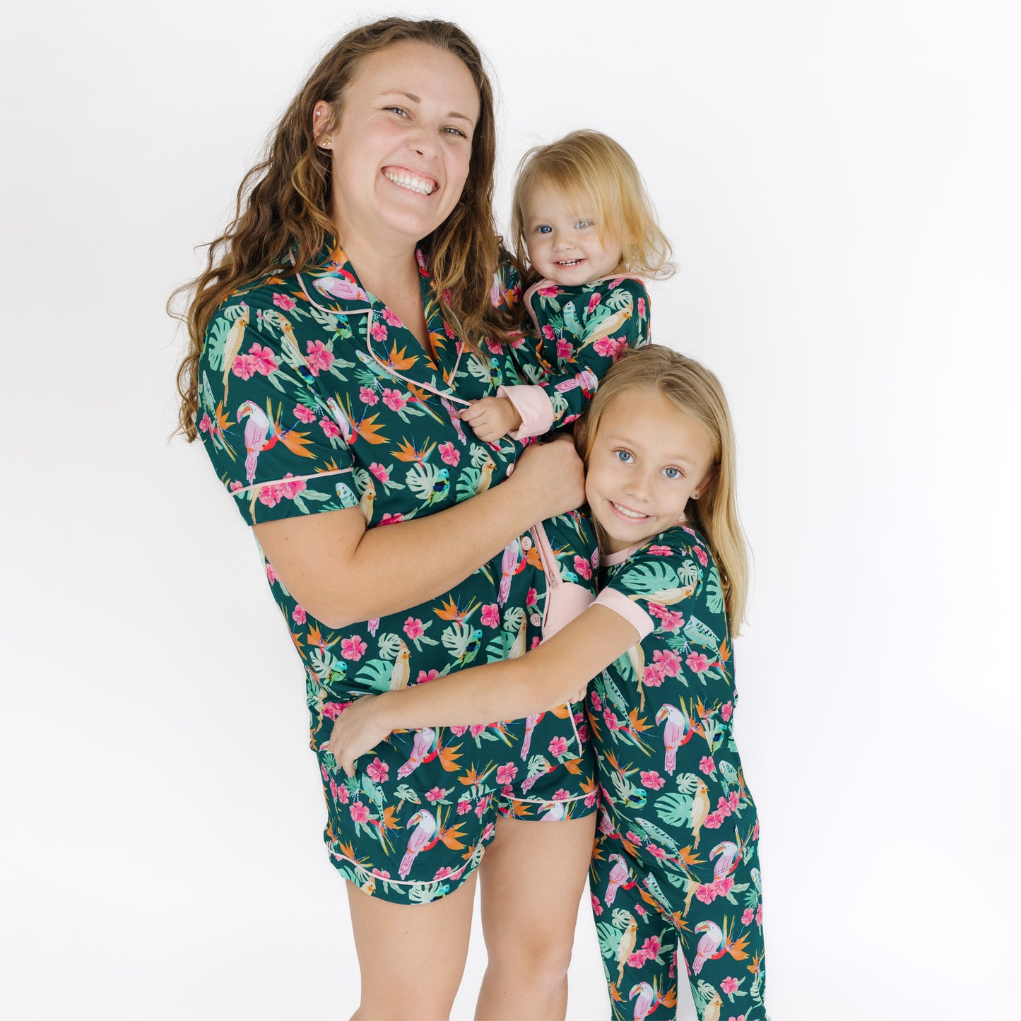 A mother and baby smiling in matching tropical bird print bamboo pajamas, perfect for slow weekend mornings.