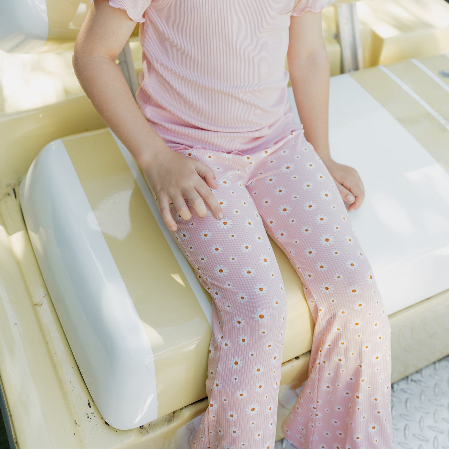 Person wearing pink polka dot pants sitting on a white surface