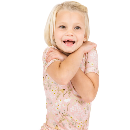 Young girl with blonde hair wearing a floral dress on a white background