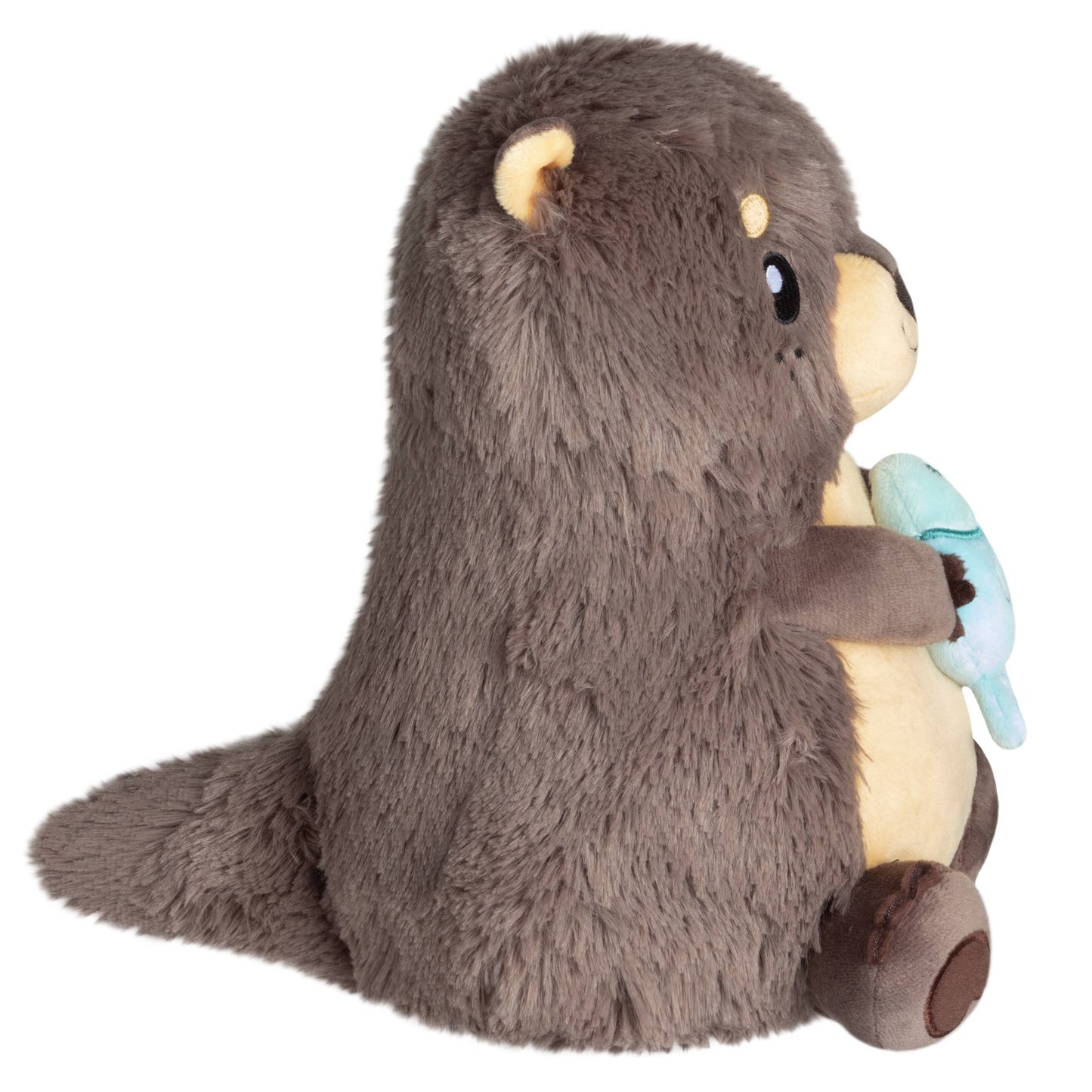 Plush toy otter holding a blue fish on a white background