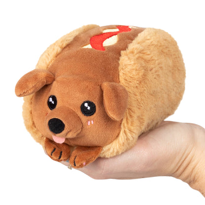 Plush dog toy held in a hand against a white background