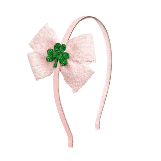 Pink headband with a large bow and green four-leaf clover on a white background