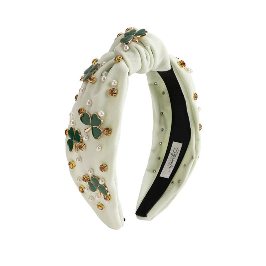 Decorative headband with green shamrock and pearl details on a white background