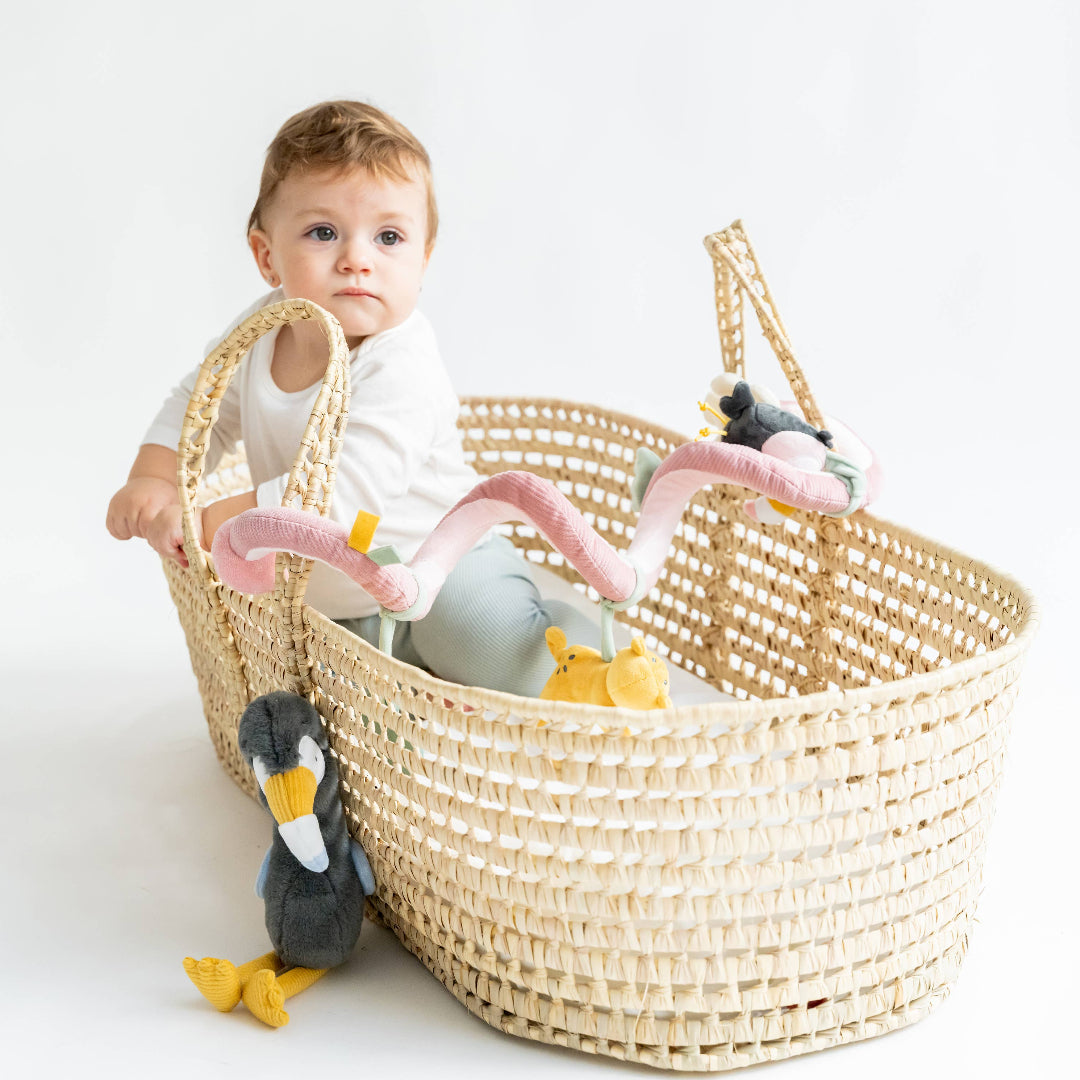 Child playing with a woven crib and toy penguins on a white background