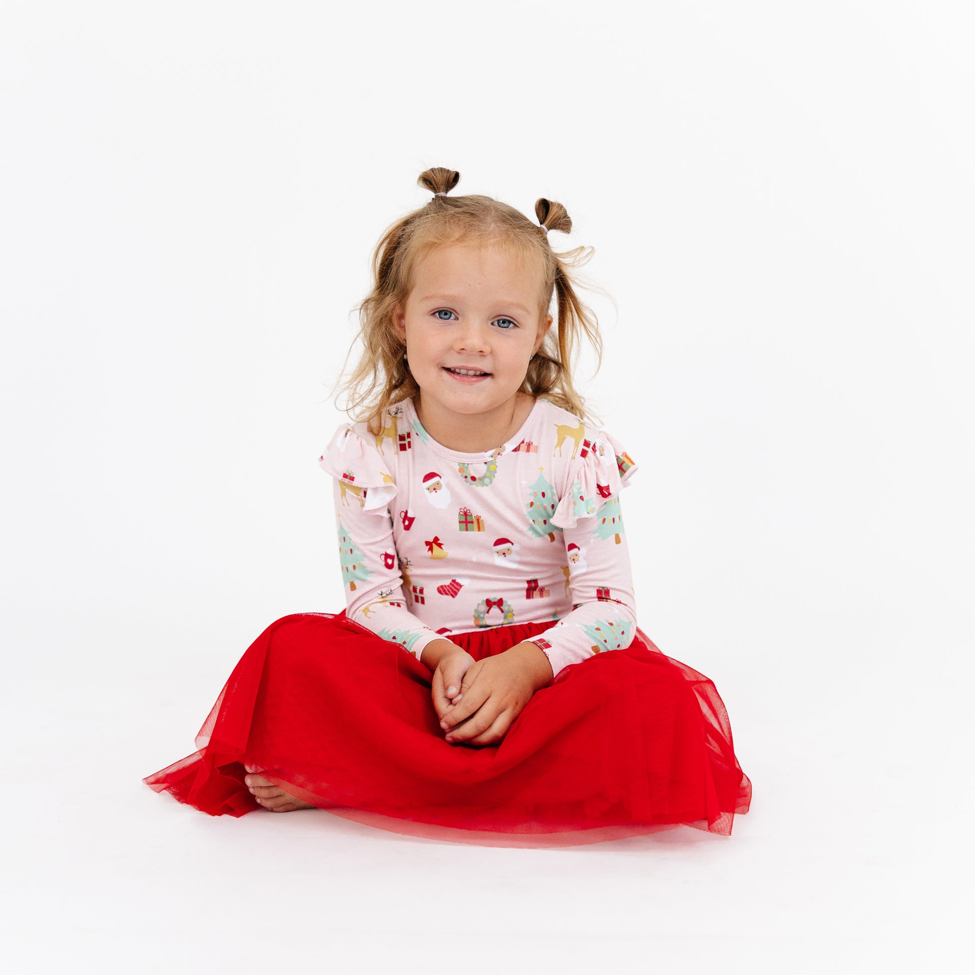 Girl sits smiling in Sugar Plum bamboo tulle dress, highlighting the cozy bamboo fabric and holiday-ready style.