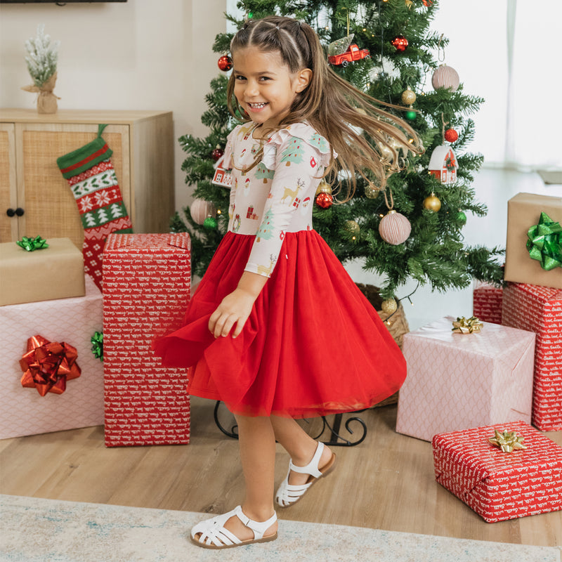 Girl twirls by the Christmas tree in the Sugar Plum bamboo tulle dress, showcasing lightweight tulle and festive charm.