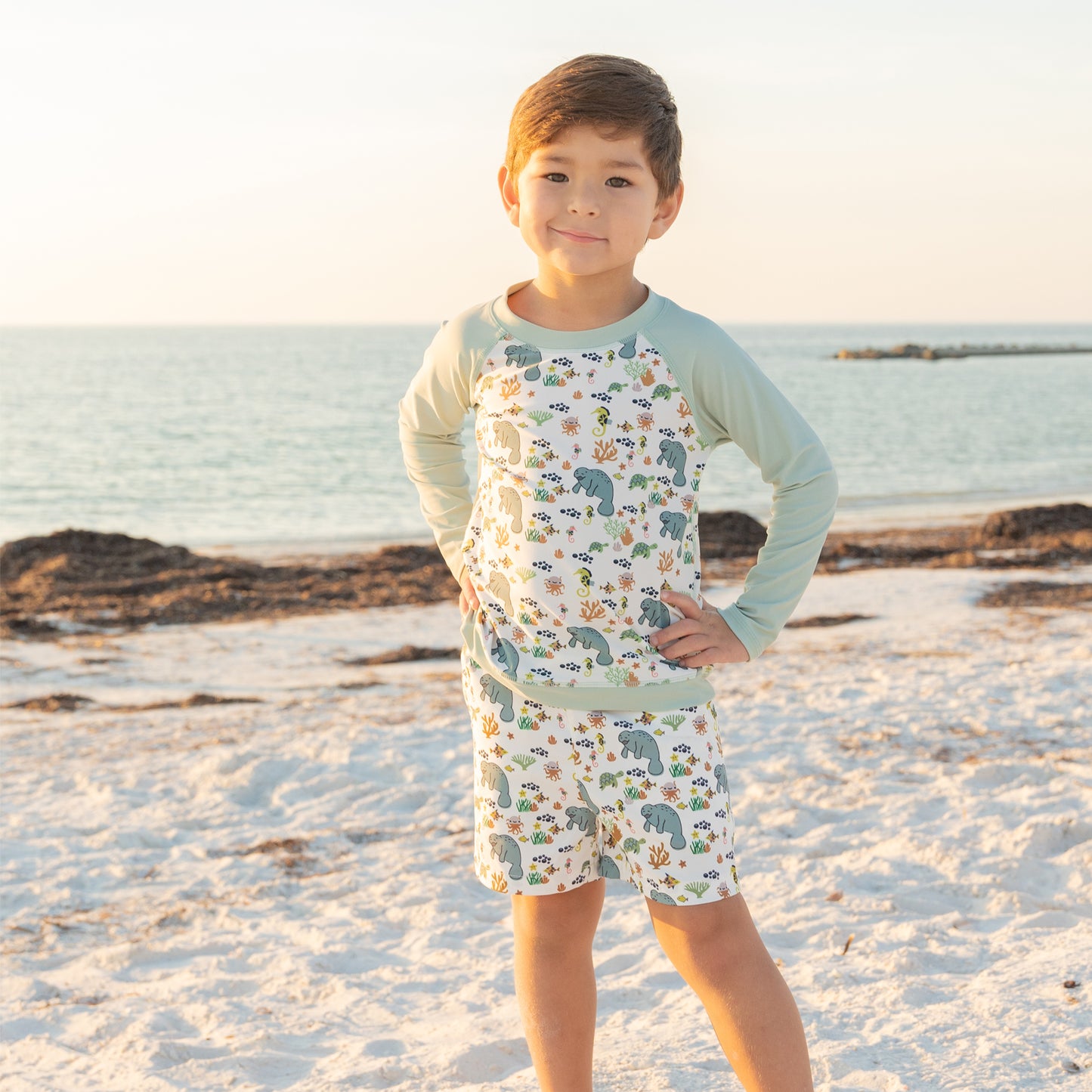 Child wearing a patterned outfit on a beach