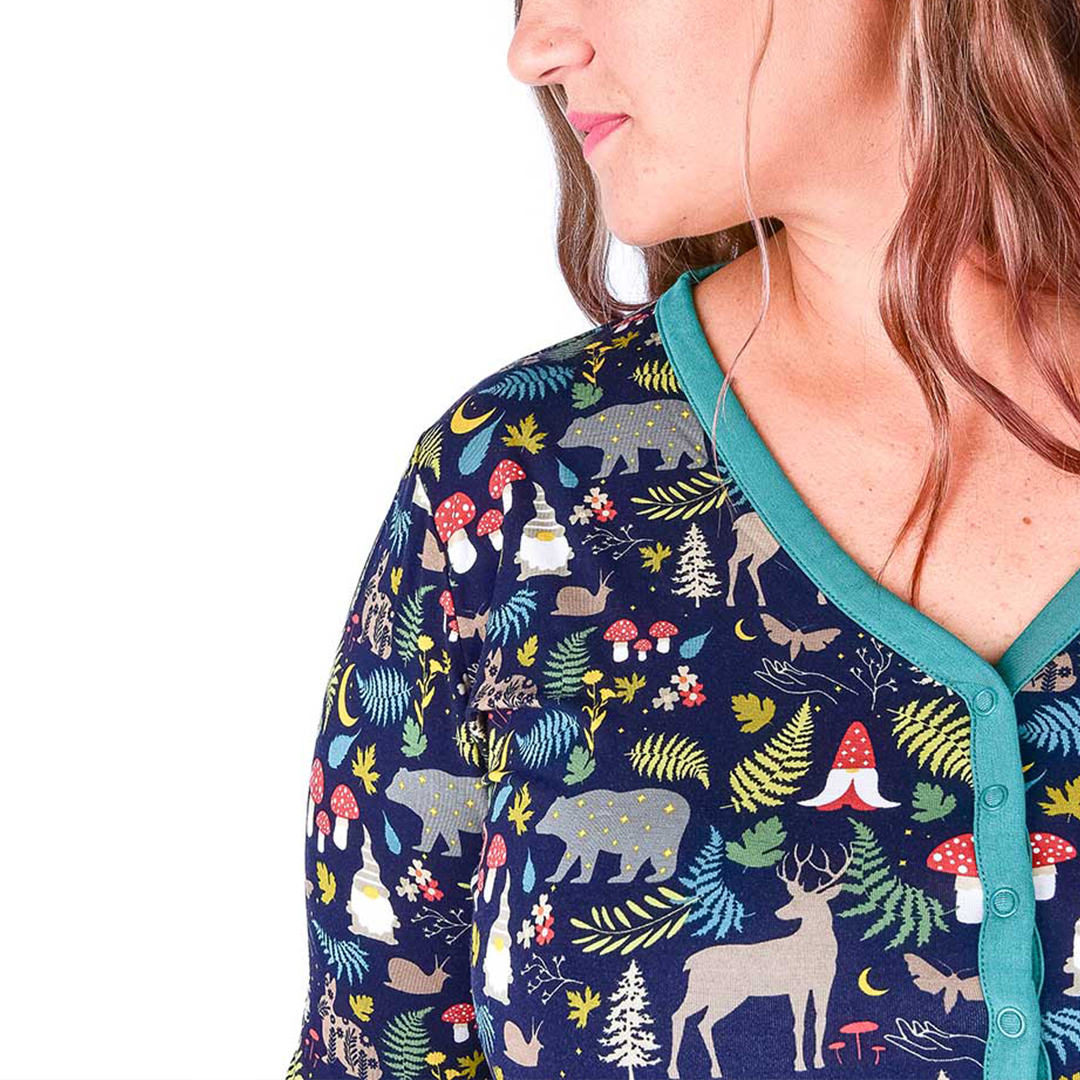 close up picture of the "night forest" women's top. the "night forest" print is a night time themed design. you can see an array of forest animals ranging from, deer, bears, bunnies, birds, forest trees and leaves, flowers, and mushrooms. there are also starts and moons scattered around to enhance the night time atmosphere. 