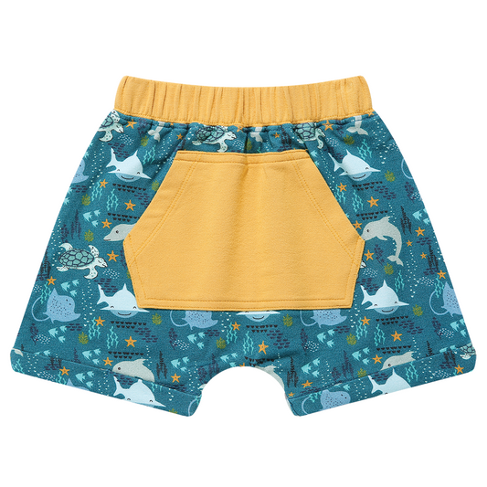 the "ocean friends" bamboo boy shorts has the "ocean friends print with a bright yellow pocket. the "ocean friends" print is a combination of dolphins, stingrays, fish, starfish, coral, bubbles, and sharks, all spread out on a deep sea blue background. 
