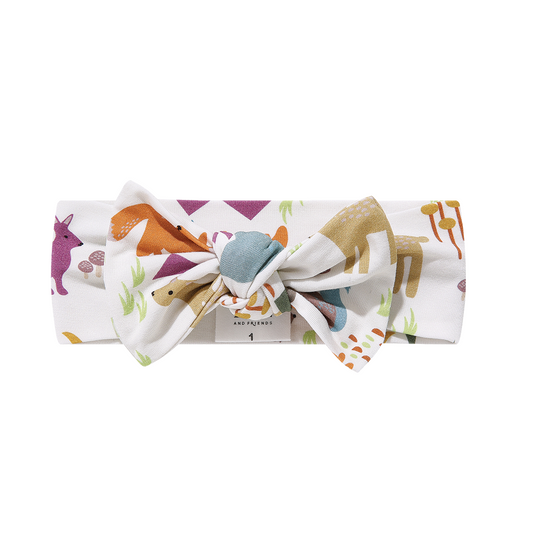 the " forest friends" bamboo baby headband. the "forest friends" print has a mix of red foxes, brown deer, blue bears, purple bunnies, trees, grass, mushrooms, acorns, moons, and other colored dots scattered over a white background. 