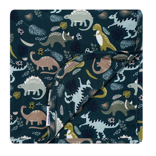 the "prehistoric friends" bamboo blanket. the "prehistoric friends" print is a mix of cute dinosaurs, eggs, and branches, all scattered on a dark green background.