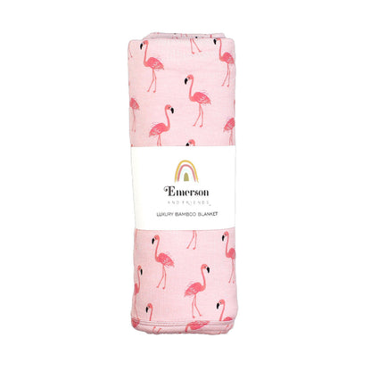 the "fancy flamingos" bamboo blanket in its packaging. the "fancy flamingos" print is a pattern of multiple pink flamingoes scattered around the print. 