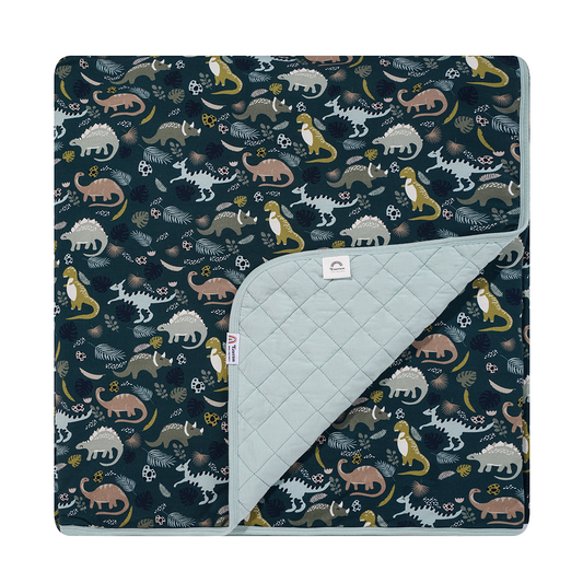 the "prehistoric friends" bamboo quilt. the "prehistoric friends" print is a mix of cute dinosaurs, eggs, and branches, all scattered on a dark green background.