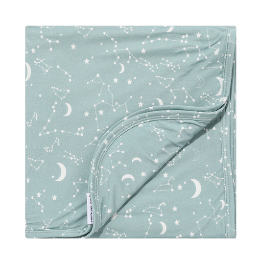 the "stargazer" bamboo blanket. the "stargazer" print is a baby blue background with a mix of moons, constellations, and stars.