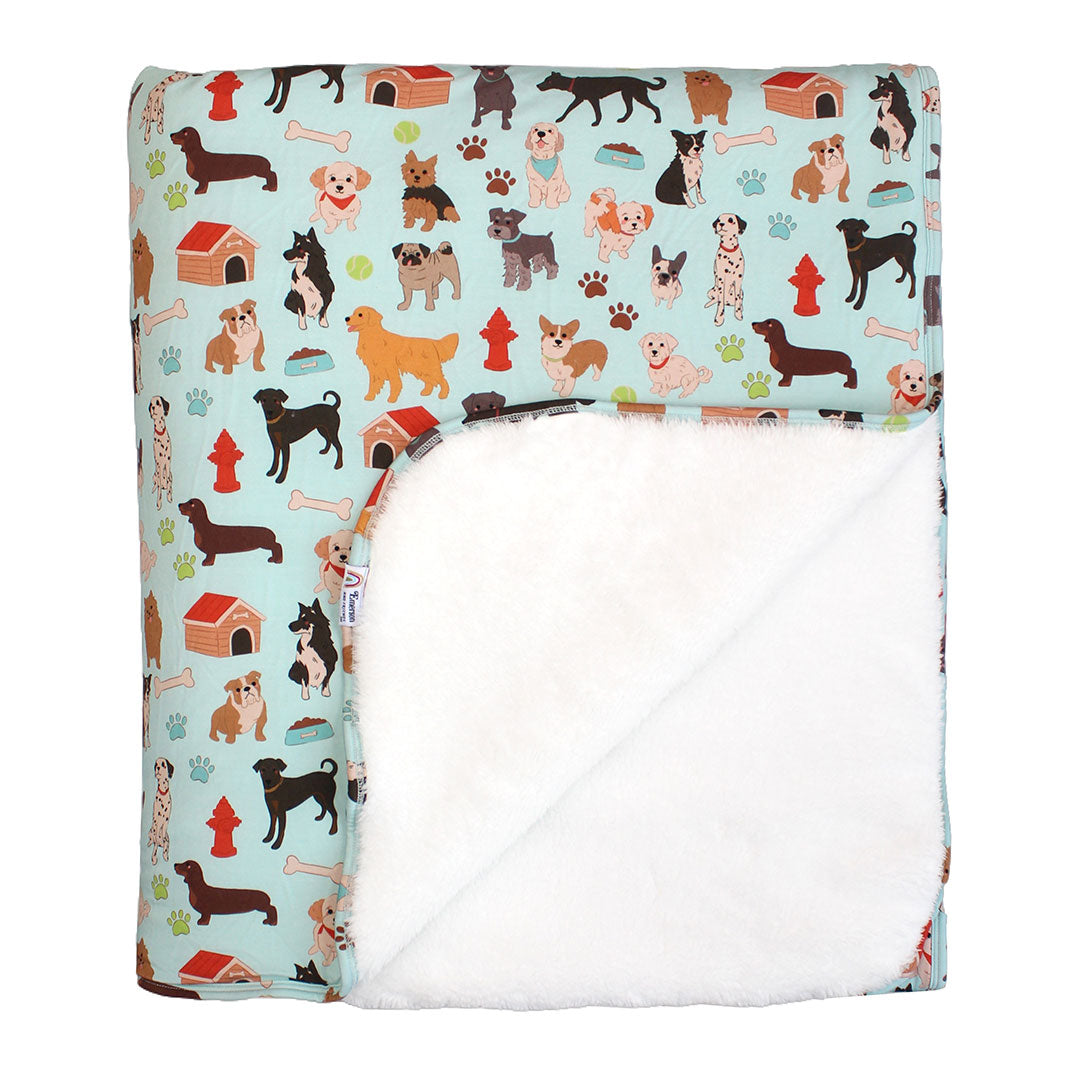 the "dogs bark" bamboo fleece blanket. the "dogs bark" print is a mix of various types of dogs, dog houses, dog bones, paw prints, dog food, and tennis balls scattered around a light blue background.