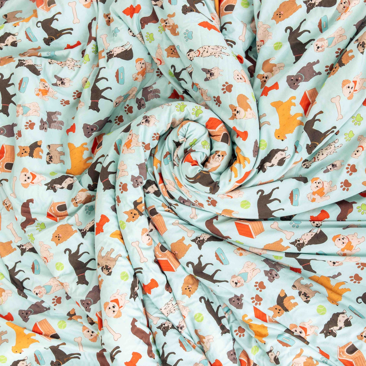 the "dogs bark" fleece blanket in a swirl. the "dogs bark" print is a mix of various types of dogs, dog houses, dog bones, paw prints, dog food, and tennis balls scattered around a light blue background.