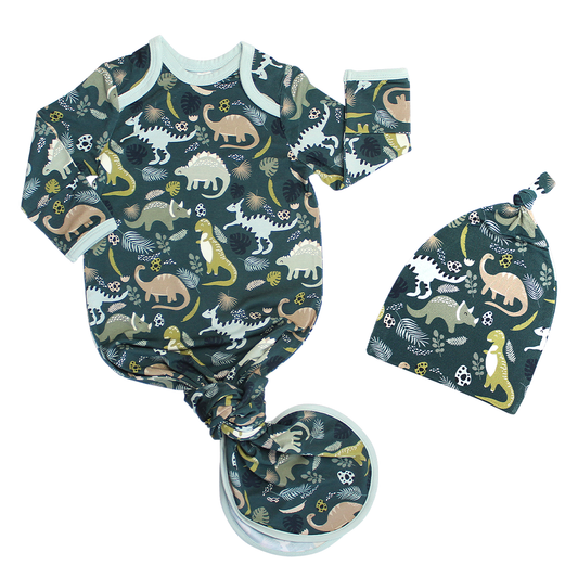 the "prehistoric friends" gown and hat set. the "prehistoric friends" print is a mix of cute dinosaurs, eggs, and branches, all scattered on a dark green background.