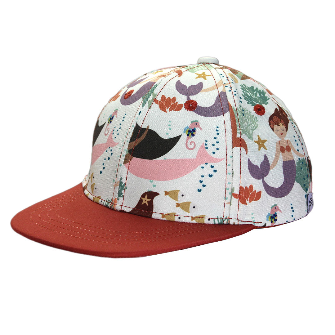 the "making waves" snapback hat. this hat has the "making waves" print on the top of the hat and the lip of it is a burnt orange/red color. the "making waves" print has a diverse spread of mermaids, sea coral, starfish, fish, and bubbles all spread out in different colors. this is all put on a beige background.