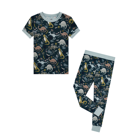 the "prehistoric friends" matching two - piece pajama set. the "prehistoric friends" print is a mix of cute dinosaurs, eggs, and branches, all scattered on a dark green background.