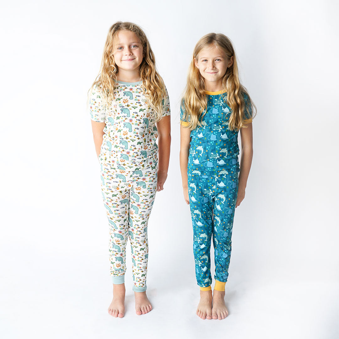 2 girls stand next to one another in their 2 piece matching sets. the girl on the left is wearing the "manatee" print and the girl on the right is wearing the "ocean friends" print. 