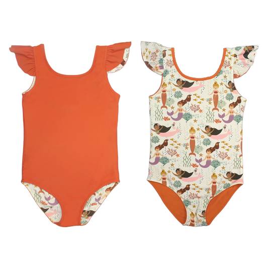 the "making waves" reversible one piece swim suit. the "making waves" print has a diverse spread of mermaids, sea coral, starfish, fish, and bubbles all spread out in different colors. this is all put on a beige background. the reverse side is a burnt orange/red color. 