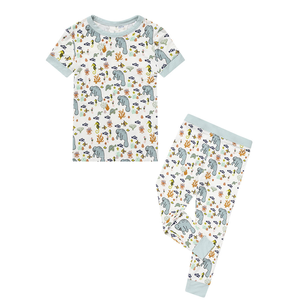 the "manatee" 2-piece matching pajama set. the print "manatee" unites the florida sea life in a majestic print. there is a variation of florida manatees, yellow and pink sea horses, yellow and pink starfish, bubbles, turtles, and coral patterned across a white background