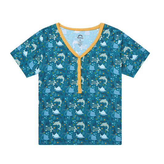the "ocean friends" women's top. the "ocean friends" print is a combination of dolphins, stingrays, fish, starfish, coral, bubbles, and sharks, all spread out on a deep sea blue background.