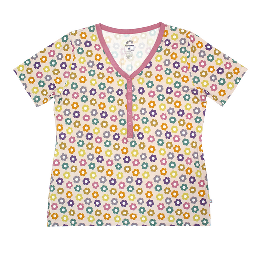 the "feeling groovy" women's top. the "feeling groovy" print is a flowered print in multiple colors. these flowers are retro and groovy. the background is light pink. 