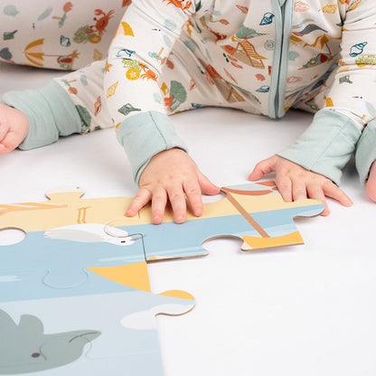 a baby wearing the "beach day" convertible, puts the "beach day" puzzle together.