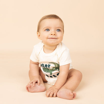 a smiling baby in the "later gator" cotton onesie. this design says "later gator" with a alligator across it. 