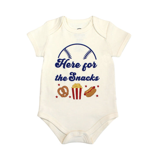 the "here for the snack" cotton onesie. this design has the phrase "here for the snacks" written across it. theres also half a baseball covering it and a pretzel, popcorn, and a hotdog on the bottom. 