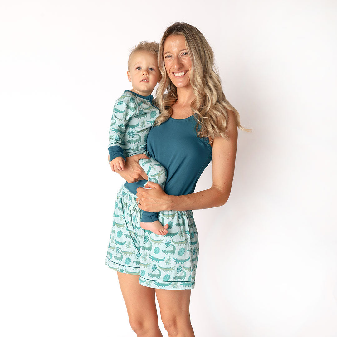 mother and her son posing in their "later gator" apparel. the "later gator" print has a mix of light and dark green alligators, leaves, and white dots scattered on a teal colored background. 