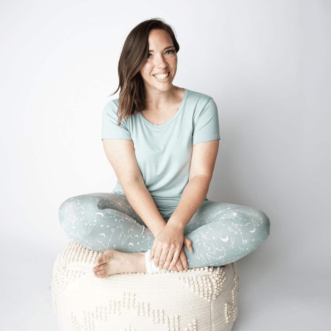 woman sits criss-cross on a cushion. the women is wearing the "blue surf" women's shirt and "stargazer" joggers. 