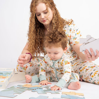 mom and baby sit on the floor and put together the "beach day" puzzle. they are both wearing "beach day" attire in the women's top, jogger pants, and the convertible. 