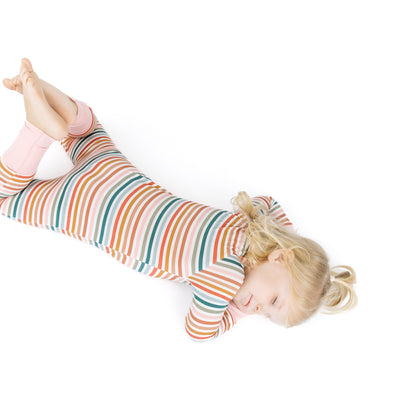 Child wearing a colorful striped outfit lying on a white background