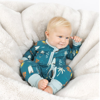 Baby wearing Surf’s Up bamboo pajamas lounging on a soft cushion