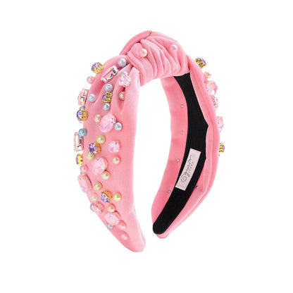 Pink headband with decorative beads and pearls on a white background