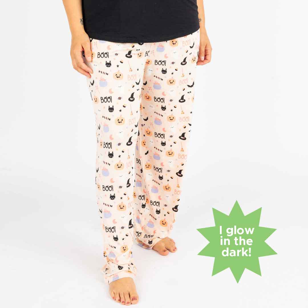 Woman standing while modeling the relaxed pants style in our Sweet and Spooky pink halloween Print featuring glow in the dark patterns, pumpkins, candy, bats and more!