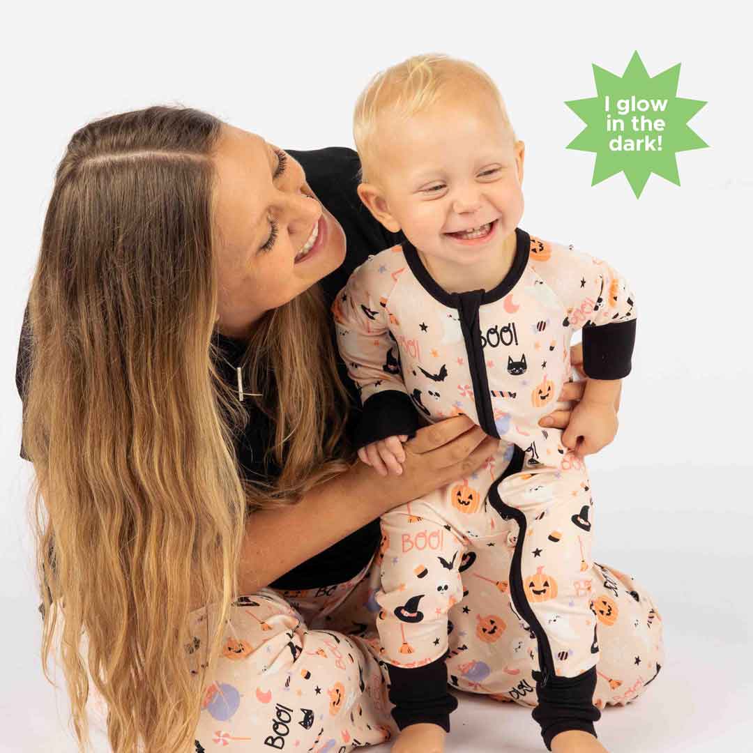 mom and baby smiling at camera and each other while wearing our Sweet and Spooky pink halloween Print featuring glow in the dark patterns, pumpkins, candy, bats and more!