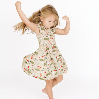 Young girl in a patterned dress dancing on a white background