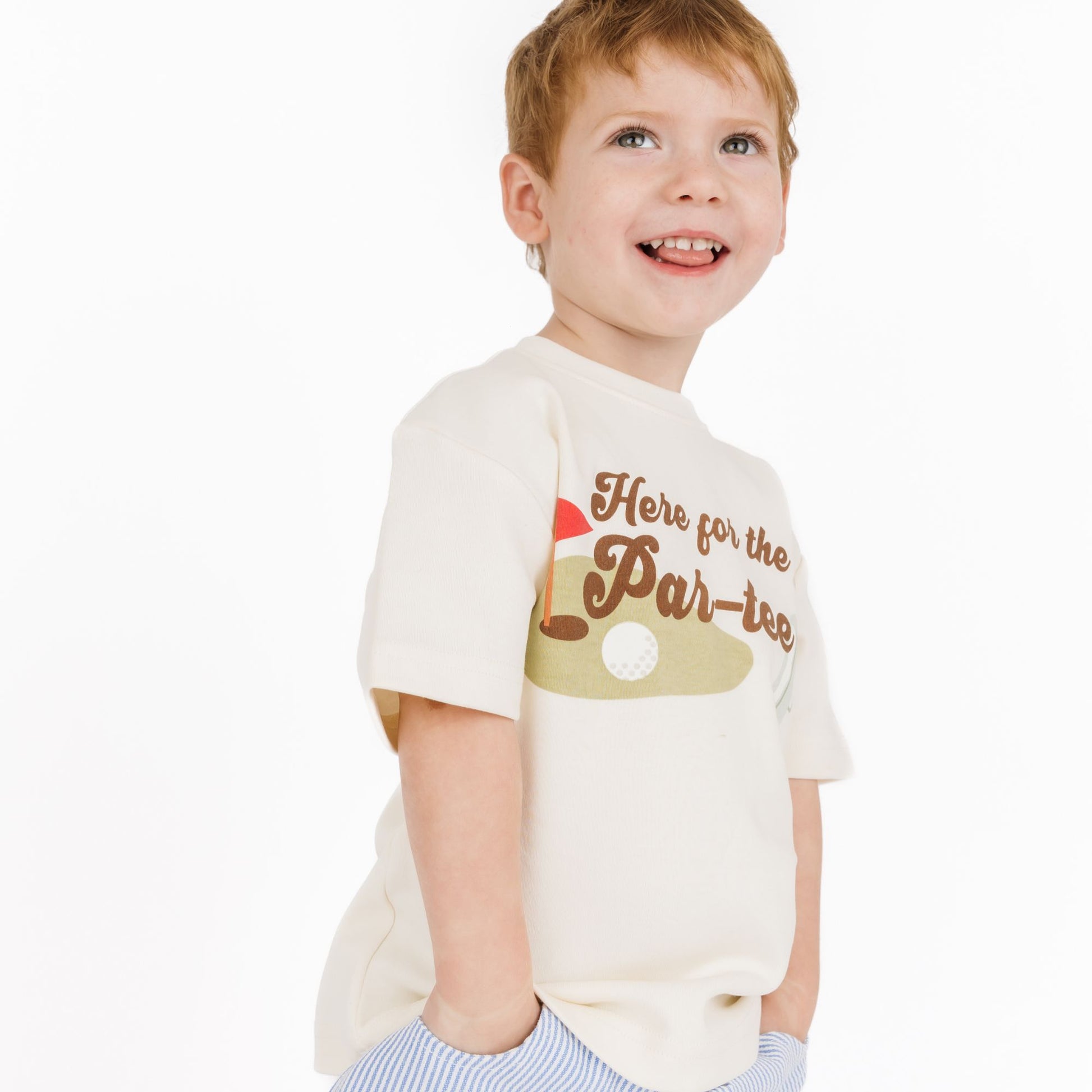 Child wearing a cream t-shirt with a printed design on a white background