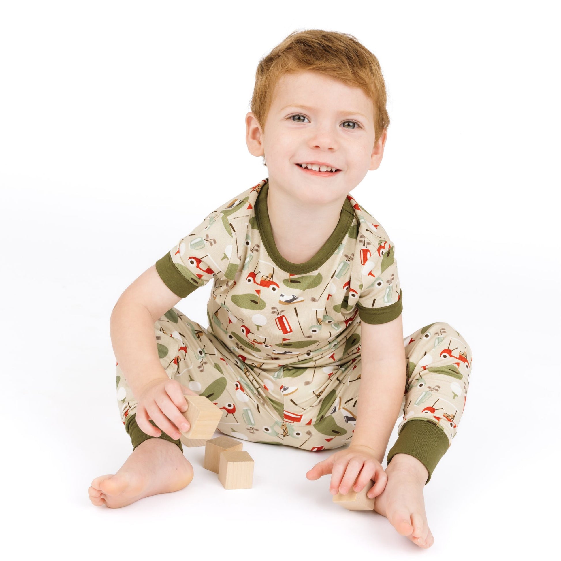 Child wearing a patterned outfit sitting on a white background